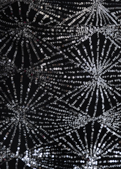 Close up swatch of fabric detail with embellished silver sequin patterns.