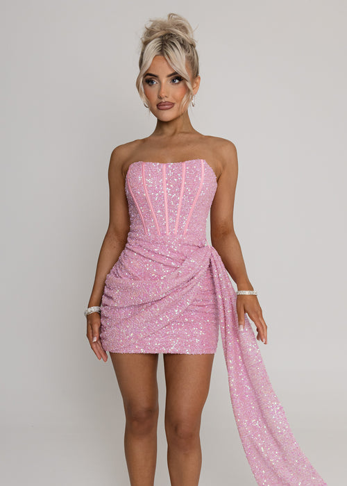 Glamourous pink sequin strapless mini dress for women with corset-style bodice, draped waist, and elegant train - fitted bodycon party and event dress. Model: 5ft2, wearing size XS UK 6.