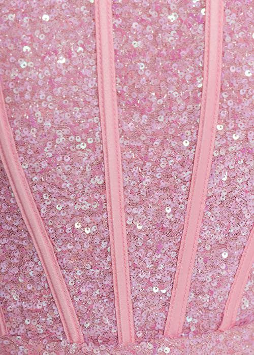 Glamourous pink sequin strapless mini dress for women with corset-style bodice, draped waist, and elegant train - fitted bodycon party and event dress. Model: 5ft2, wearing size XS UK 6.