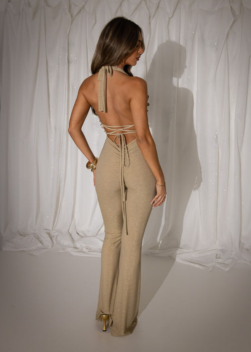 Women's gold lurex sparkly jumpsuit. Halterneckline with V neckline which is a plunge fit with ruffle detail. Figure hugging fit with flared leg shape on legs.