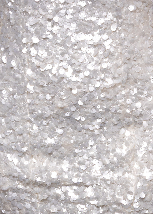 Close up fabric swatch of white sequin mini dress. 