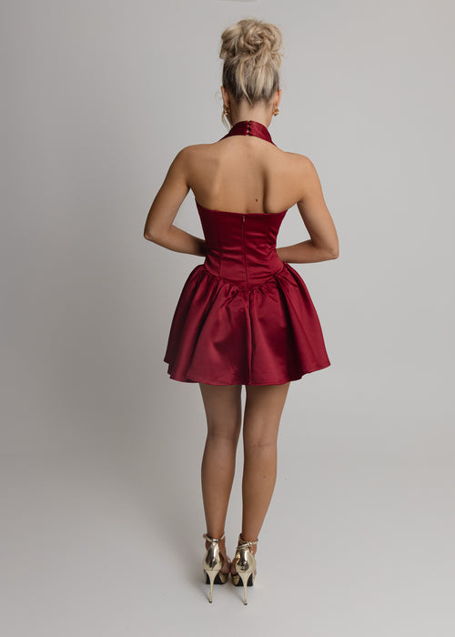 Women's wine halterneck skater style mini dress with drop waist and pleated skirt.