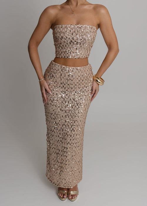 Women's rose gold embellished two piece set with bandeau style crop top fully embellished with sequins and a high waist rose gold maxi skirt fully embellished with sequins. Model is 5ft2' and wears a size XS 6.