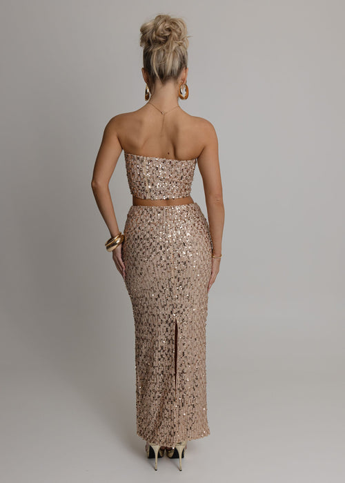Women's rose gold embellished two piece set with bandeau style crop top fully embellished with sequins and a high waist rose gold maxi skirt fully embellished with sequins. Model is 5ft2' and wears a size XS 6.