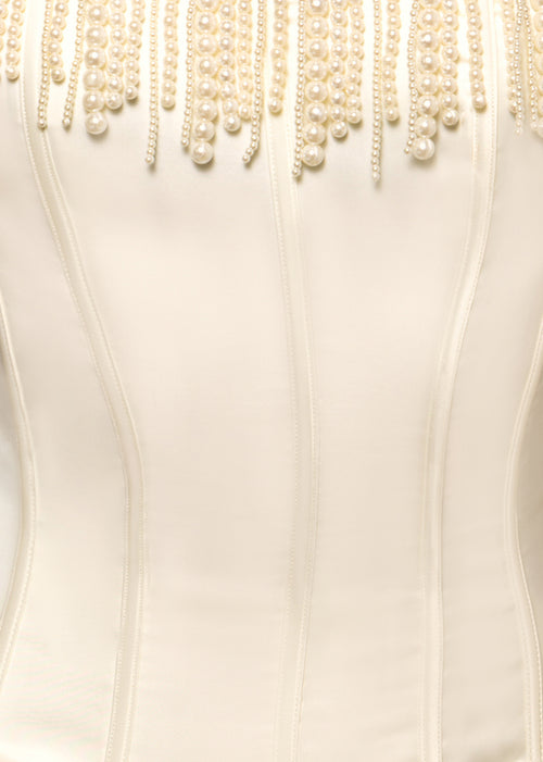 Close up detail of ivory satin fabric and pearl embellishments. 