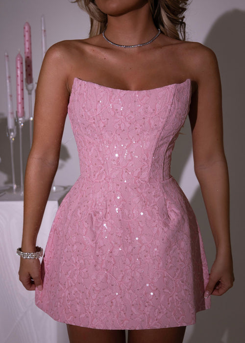 Women's pink structured strapless mini dress with corset bodice and skater style skirt. Pink lace fabric with sparkly pink sequins woven into the fabric. Model is 5ft2' and wears a size XS 6.