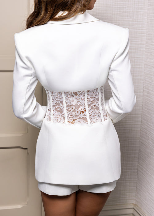 Women's white blazer two piece suit set with tailored blazer, white lace waist detail and white shorts.