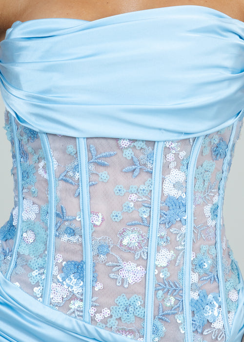 Close up details of prom gown with sequin floral embellishments and blue embroidery leaf patterns.