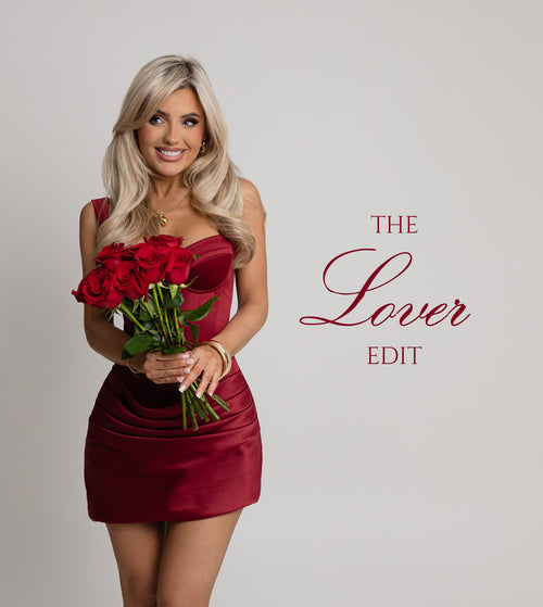 Woman standing against a white backdrop in a studio, wearing a red satin fitted mini dress holding a bunch of red roses for a Valentine's day theme.