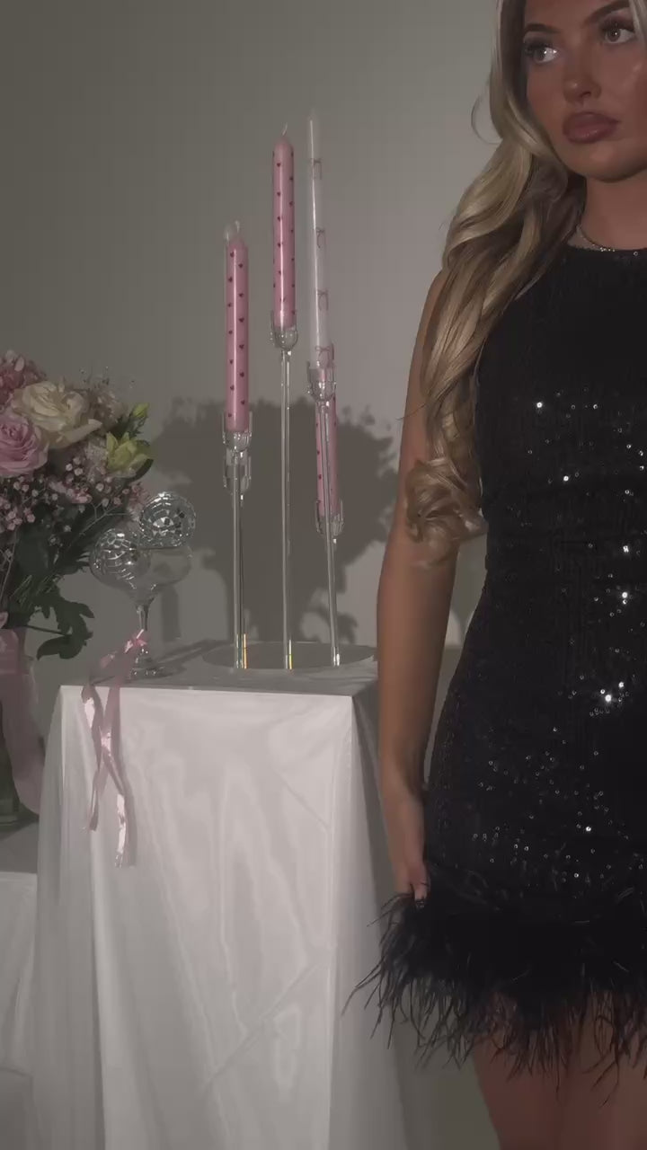 Women's black sequin sparkly mini dress with black feather trim. Bodycon fit with round neckline and open back. Model is 5ft2' and wears a size XS 6.