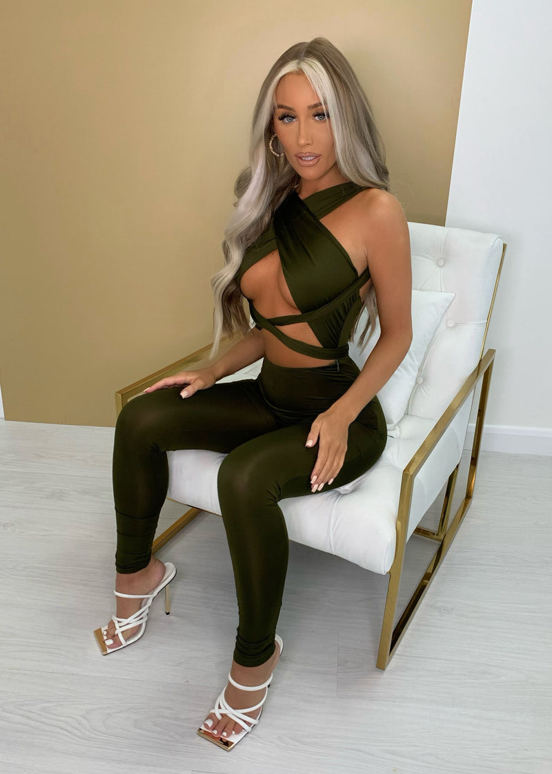 khaki green jumpsuit, with multi-way straps and a zip fastening, made from a stretchy jersey material. Model wears a size XS as shown in the image. 